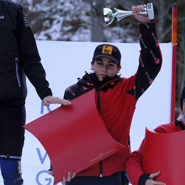 un giovane sciatore esibisce la coppa vinta
